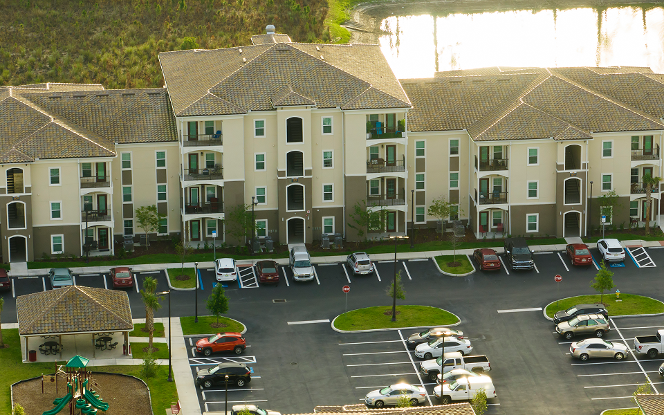 Modern senior living residence with warm wood cladding, glass balconies, and a landscaped entrance.