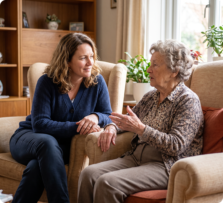 A team member and resident share a warm conversation in a bright community lounge.
