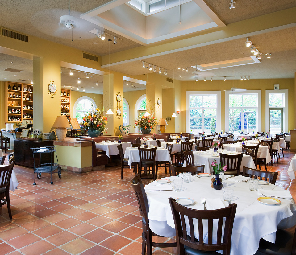 Residents share a meal together in a bright, refined senior living dining room.