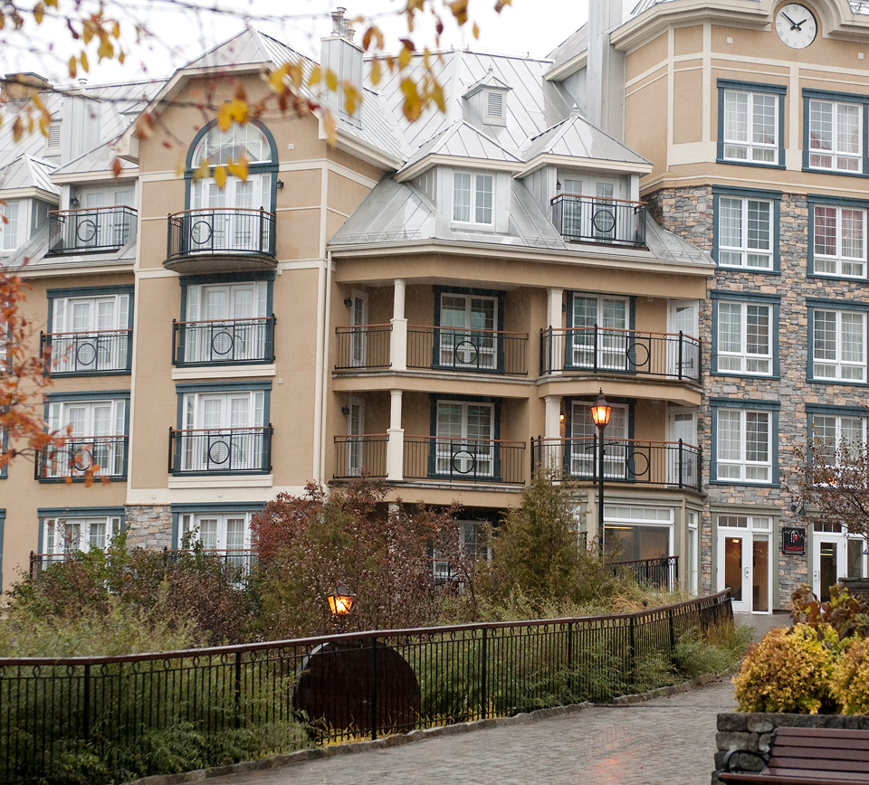 Multi-story senior living residence with stone accents, wrought-iron balconies, and landscaped grounds.